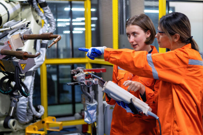Technikerinnen in einer Fabrik arbeiten an einem Roboter